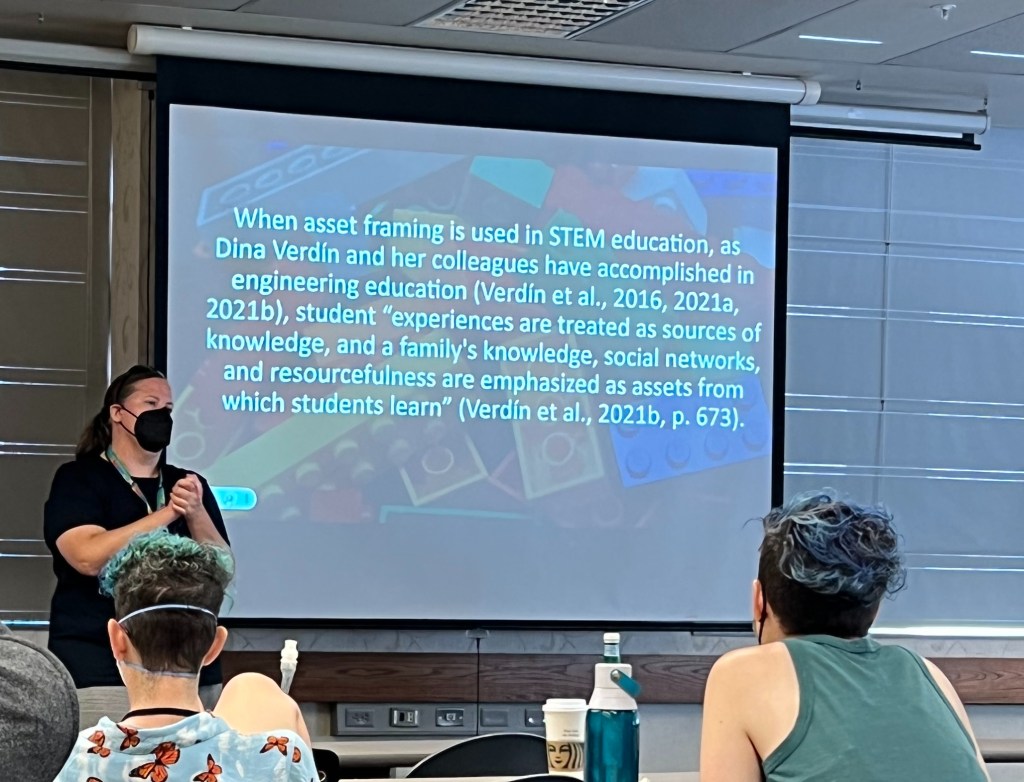 Rissa (white woman, long brown hair, wearing a black mask) talking about asset framing in STEM ed